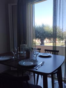 阿查拉维Olive Garden Studios & Apartments的餐桌,带盘子和玻璃杯,窗户