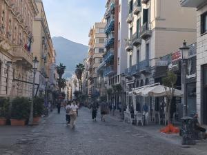 萨莱诺Salerno4Seasons的一群人沿着街道走着,街道上有许多建筑