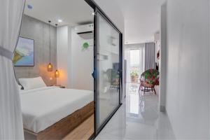 岘港MTR Apartment & Hotel的卧室配有白色的床和玻璃门