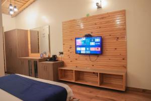 比姆塔尔The Lake Ambience Resort的卧室设有木墙电视