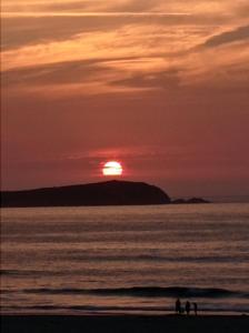 拉科鲁尼亚Alojamiento PLAYA DE PANTIN的日落时分两人站在海滩上