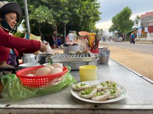 Ninh HảiNinh Chử House的一位在餐桌上准备食物的女人,配上一盘食物