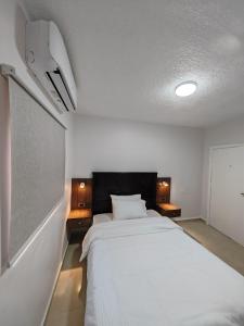 瓦迪穆萨埃及艳后酒店的卧室配有一张白色大床和两盏灯。
