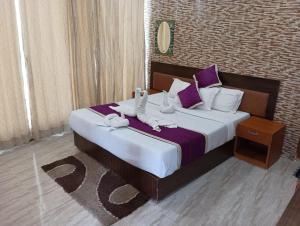 哈夫洛克岛Gold India Beach Resort的一间卧室配有一张大床,提供紫色和白色枕头
