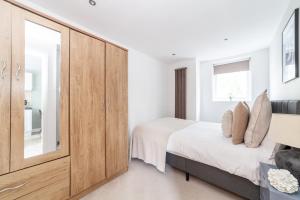 布罗姆利The Wandsworth Flat的一间卧室配有一张床和一个大型木制橱柜