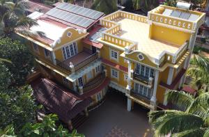 马焦茹达The Royal Oasis Goa的棕榈树黄色房子的顶部景色