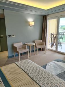 瑞维尼亚克Suite Deluxe vue sur Golf的酒店客房带一张床、一张桌子和椅子