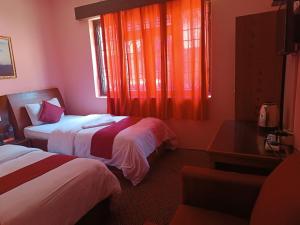 TāplejungThe hotel mountain Taplejung的酒店客房设有两张床和窗户。