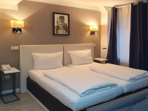 杜塞尔多夫Rheinmetropole Hotel的一间卧室配有带白色床单和枕头的床。