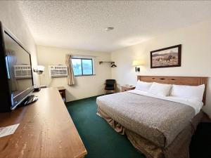 沃尔夫波因特Homestead Inn的配有一张床和一台平面电视的酒店客房