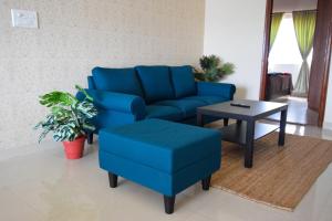 班加罗尔StayMazing-1,2 & 3 BHK AC Apartments in Hebbal-5mins to Manyata-30mins to Airport的客厅配有蓝色的沙发和桌子