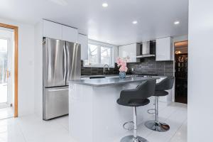 布罗瑟德Gorgeous 5 Bedroom House的厨房配有不锈钢冰箱和2个吧台凳