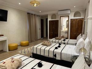 马拉喀什Riad Medina Art & Suites的酒店客房设有两张床和电视。