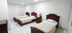 库库塔Hotel Exelsior的带3张床和白色墙壁的客房