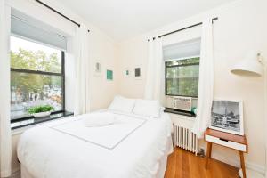纽约Three Bedroom West Village Townhouse的白色卧室设有一张大床和两个窗户