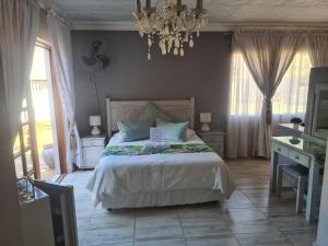 BrakpanRoyal Villa Guesthouse的一间卧室配有一张大床和一个吊灯。