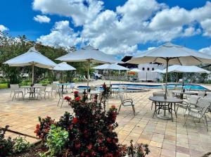 阿雷亚Hotel Fazenda Triunfo的一个带桌椅、遮阳伞和游泳池的庭院