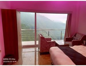 西姆拉Hotel Candle Wood, Shimla的客房设有一张床和一个美景阳台