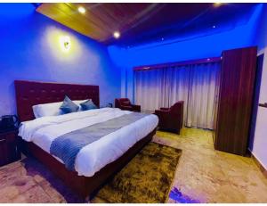西姆拉Hotel Candle Wood, Shimla的一间蓝色客房内配有一张大床的卧室