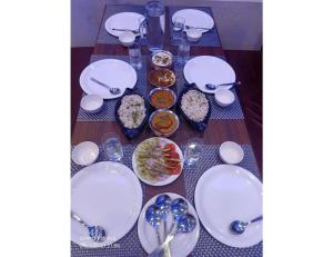 西姆拉Hotel Candle Wood, Shimla的餐桌,带白板和碗的食物