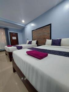 暹粒尼卡旅馆的一间卧室设有三张床和一堵墙