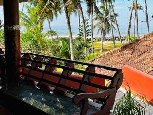 瓦尔卡拉Maadathil Cottages & Beach Resort的坐在门廊上看海滩的长凳