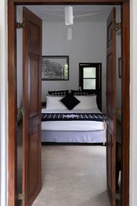 科伦坡“27”火焰树城市绿洲住宿加早餐旅馆的一间卧室配有一张带白色床单的大床