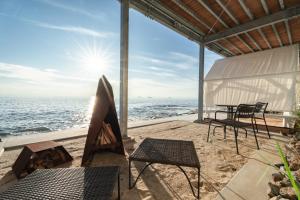 NomaGlamping＆Resort WOOD DESIGN PARK NOMA的海滩上带桌椅的庭院
