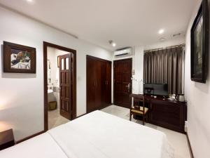 胡志明市Hoang Yen Hotel - Phu My Hung的一间卧室配有一张床、一张书桌和一台电视