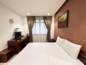 胡志明市Hoang Yen Hotel - Phu My Hung的卧室配有一张白色大床和一张书桌