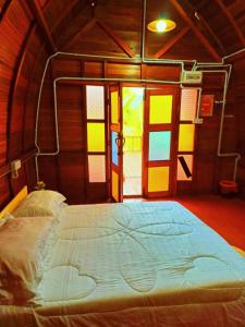 浮罗山背LBA chalet的一张大床,位于带彩色窗户的房间里