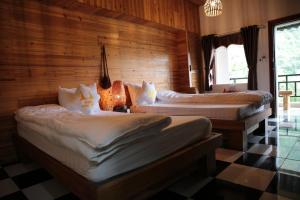 河江Ha Giang Historic House & tour的配有木墙和 ⁇ 木地板的客房内的两张床