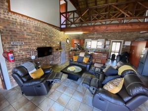 玛洛斯帕克Nghala Self-catering Holiday Home的客厅配有皮革家具和砖墙