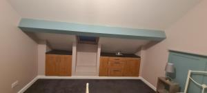 巴恩斯利Charming 1-Bed Apartment in Barnsley的厨房设有蓝色的天花板和木制橱柜。