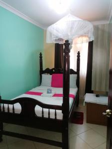 KakamegaMilimani Greens Inn的一间卧室配有一张带天蓬的床