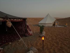BadīyahThousand Stars Desert Camp的沙漠中的帐篷,沙子里有手电筒