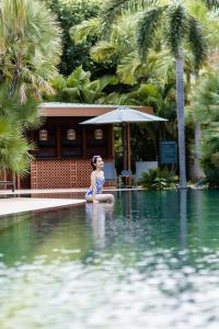 暹粒Angkor Grace Wellness Resort的坐在游泳池的水中的女人
