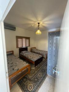 Al KhuraybahWadi Al-Nakhil Hostel的一间卧室配有两张床和吊灯。