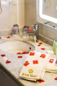 安曼Rival Hotel Amman的浴室水槽,上面有红色鲜花的毛巾