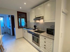 厄姆河畔的德廷根Vali‘s Apartment One的厨房配有白色橱柜和炉灶烤箱。