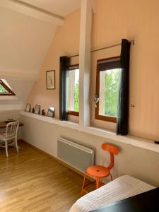 BaugéLe Logis de la Chouette的客房设有2扇窗户和1把橙色椅子。