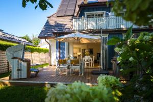 普雷罗Traumhaus Auri in Prerow Ostsee auf dem Darß mit Kamin und Sauna und Garten的庭院配有桌椅和遮阳伞。