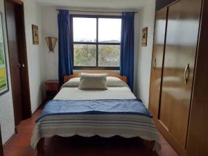 拉帕洛马Apto frente al mar en La paloma的一间卧室配有一张带蓝色窗帘的床和一扇窗户
