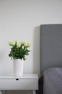奥卢Lovely 2R apartment的一张白色花瓶,在床边的桌子上放着鲜花