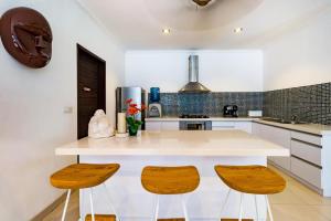塞米亚克Sari Temuku Villa的厨房配有白色的柜台和2张木凳