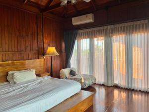 帕府Bann Rai I Na的一间卧室配有一张床、一把椅子和窗户。