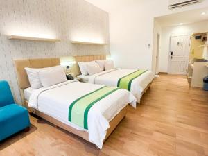 普禾加多Hotel Wisata Niaga Campus的两张位于酒店客房的床,配有蓝色椅子