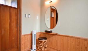 别府Kamegawa Onsen HATAGO Yuyu的浴室设有圆形镜子和凳子