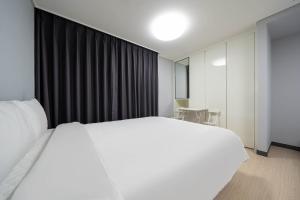 丽水市Myeongga Ubleth Hotel的卧室配有白色的床和黑色窗帘