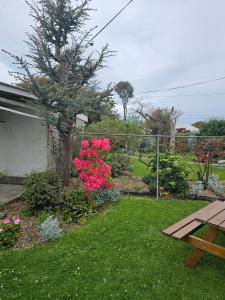 奥玛鲁维拉度假屋的一座种植了粉红色花卉并配有野餐桌的花园